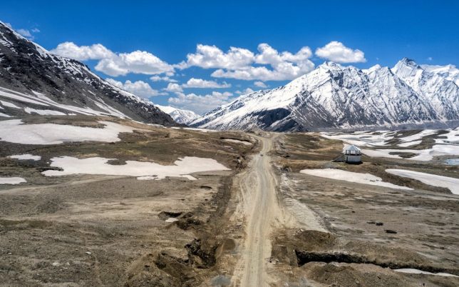 Breathtaking view of snow-capped mountains and rugged terrain in Zanskar, India, under a clear blue sky.